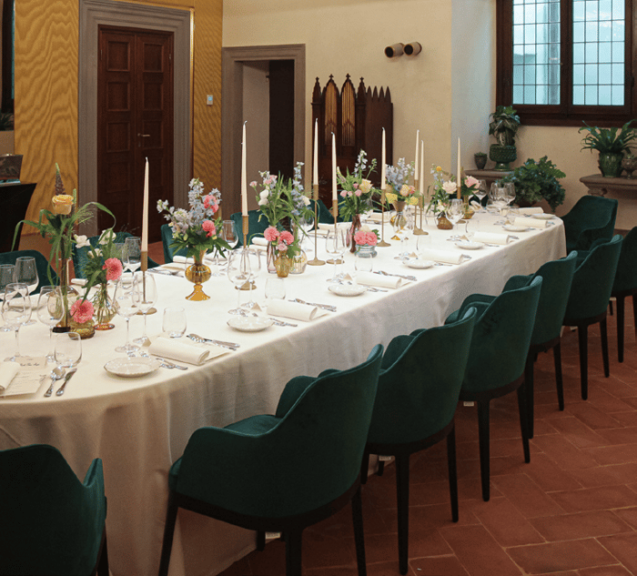 La sala della tavola rotonda apparecchiata con tovaglia bianca, composizioni floreali e candele
